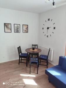 a room with a table and chairs and a clock on the wall at Apartament Anastazja in Koszalin