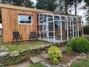 ein kleines Haus mit zwei Stühlen und viel Glas in der Unterkunft Indigo Lodge - Aberdovey in Aberdyfi