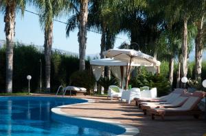 a swimming pool with lounge chairs and an umbrella at Villa Papardo in Giarre
