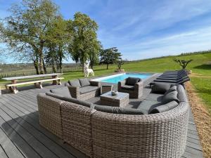 un patio con muebles de mimbre junto a una piscina en Le domaine Reine Sully, en Saint-Quentin-de-Caplong