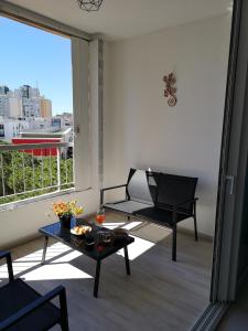 balcón con sofá, mesa y ventana en Aux 4 bleutées, en Niza