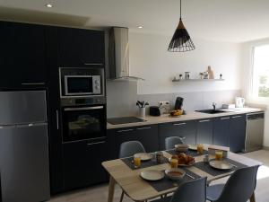 una cucina con armadi neri e tavolo con sedie di Aux 4 bleutées a Nizza