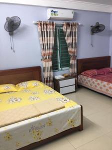 a bedroom with two beds and a fan at Nhà nghỉ Thường Nga in Cat Ba