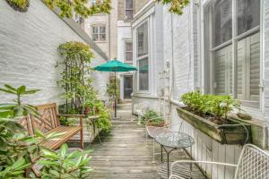 Mount Vernon Apartment Rear في بالتيمور: فناء به طاولات وكراسي ومظلة