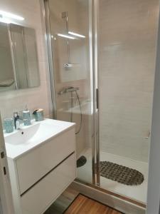 La salle de bains blanche est pourvue d'une douche et d'un lavabo. dans l'établissement Studio confortable, face mer, proches commerces, à Pornichet