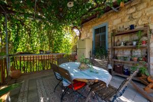 a patio with a table and a fence with vines at Hemdatya Stone Suites In The Galilee in Ilaniya