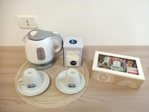 B&B Casa Denittis في بيسكيتشي: طاولة مع وعاء الشاي وأكواب وصندوق