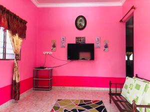 ein rosafarbenes Zimmer mit einer Uhr an der Wand in der Unterkunft Homestay TokAbah in Pasir Puteh