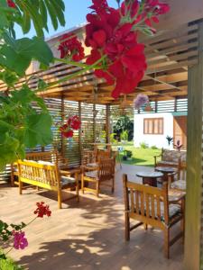 un patio con bancos, mesas y flores rojas en Condominio Vila Lila, en Garopaba
