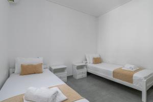 twee bedden in een kamer met witte muren bij Emanouela's apartement in the center of Adamas in Adamas