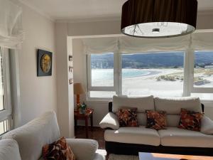 a living room with a couch and a large window at Rompeolas in Laxe