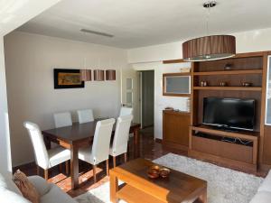 a living room with a dining room table and a television at Rompeolas in Laxe