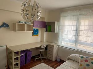 a bedroom with a desk and a bed and a chandelier at Rompeolas in Laxe +13 photos