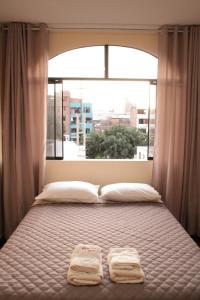 una cama con dos toallas delante de una ventana en Hospedaje turístico Peruvian Wasi en Lima