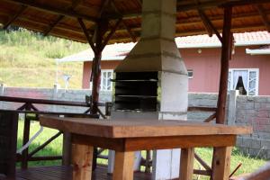 una mesa de madera con un horno de pizza en la cubierta en Pousada Aconchego serrano, en Rio Rufino