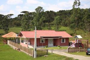 una casa con techo rojo y parque infantil en Pousada Aconchego serrano, en Rio Rufino