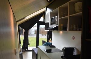 a kitchen with a counter and a microwave in a room at Tiny House in het groen, aan zee met privé Hottub in Callantsoog