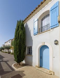 una casa con una puerta azul y un árbol en Marina Aigues-Mortes ****, en Aigues-Mortes