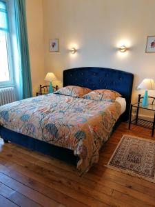 a bedroom with a bed with a blue headboard at Au Puy Des Vérités in Lapalisse