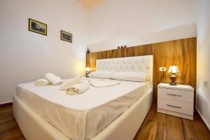sypialnia z dużym białym łóżkiem z drewnianym zagłówkiem w obiekcie THE OLD TOWN CLOCK w Gjirokastrze