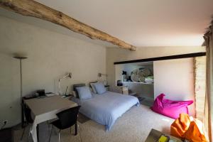 a bedroom with a bed and a desk with a pink bag at B&B Contemporain Le Jardin in Vaison-la-Romaine