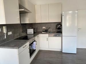 a kitchen with white cabinets and a white refrigerator at Apartment an der Weserpromenade - Schlachte - Parkplätze in Bremen