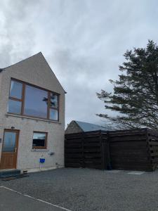 una casa con una puerta de madera y una valla en Valhalla Brae, 3 Bed House on NC500 with Beautiful Castle and Sea Views, en Keiss