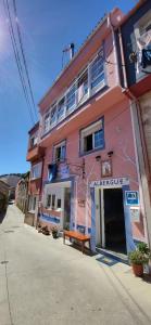 a pink building with a bench in front of it at Albergue de Peregrinos La Espiral in Finisterre