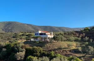 una casa su una collina con una montagna sullo sfondo di Gorgeous private Villa with sea view! ad Andro