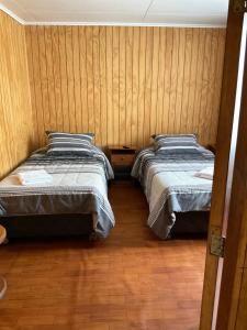 2 letti in una camera con pareti in legno di Hostal Balmaceda a Punta Arenas