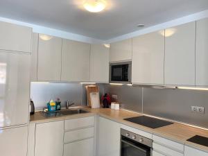 una cocina con armarios blancos y electrodomésticos de acero inoxidable en Super cool villa in Los Cristianos, en Los Cristianos