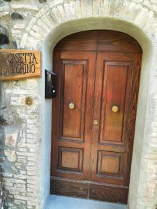 una porta di legno in un muro di pietra con un cartello di Casetta di Ghino a Radicofani