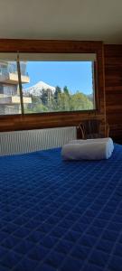 1 dormitorio con cama azul y ventana grande en Hotel Costanera Pucón, en Pucón