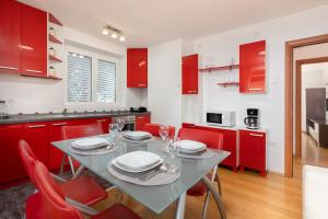 cocina con armarios rojos, mesa y sillas en Apartments Banje Beach, en Dubrovnik