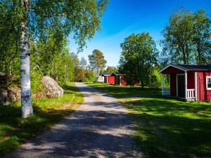 un chemin de terre avec deux bâtiments rouges et un arbre dans l'établissement Lufta Camping & Restaurang, à Ånäset