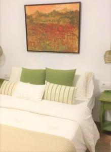a white bed with pillows and a painting on the wall at Can Xito in Sencelles