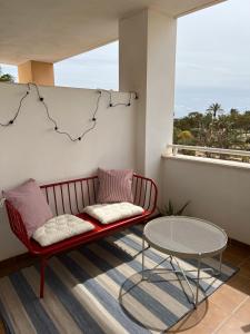 un banco rojo sentado en un balcón con una mesa en APARTAMENTO TOTALMENTE NUEVO JUNTO AL MAR - Cabo de Gata en Retamar