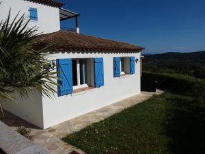 biały dom z niebieskimi oknami i palmą w obiekcie Luciana w mieście La Croix-Valmer