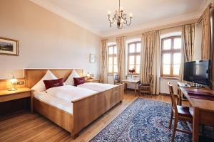 a bedroom with a bed and a desk and a television at Hotel & Restaurant Waldschloss in Passau