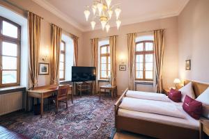 - un salon avec un lit, un bureau et une télévision dans l'établissement Hotel & Restaurant Waldschloss, à Passau