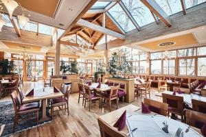 un restaurante con mesas y sillas de madera y ventanas en Hotel & Restaurant Waldschloss, en Passau