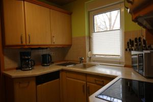 eine Küche mit Holzschränken, einem Waschbecken und einem Fenster in der Unterkunft Ferienwohnung Engelsbach in Engelsbach