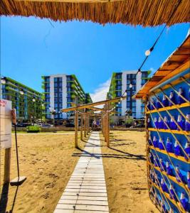 a beach with a straw umbrella and some buildings at Opium STUDIO ALEZZI in Mamaia Sat/Năvodari