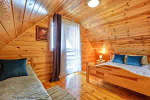 a log cabin bedroom with two beds and a window at Słoneczny Brzeg Polańczyk Domki 8-osobowe in Polańczyk