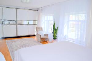 1 dormitorio blanco con 1 cama blanca y 1 silla en Garden Cottage near Beach, Airport, en Baku