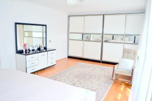 a white bedroom with a dresser and a chair at Garden Cottage near Beach, Airport in Baku