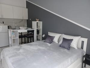 a white bedroom with a large bed with purple pillows at Summer rest in Split
