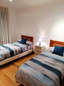 a bedroom with two beds and a lamp on a wooden floor at Precioso apartamento con piscina y jardín frente a la Toja in O Grove