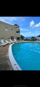 ein großer blauer Swimmingpool neben einem Gebäude in der Unterkunft Kris’o Super Studio in Ocho Rios