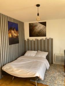 a bed in a bedroom with a striped wall at Studio avec grande terrasse et jardin privatif au Pyla in La Teste-de-Buch